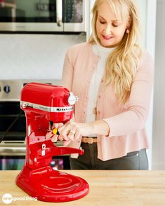 a woman standing in front of a red mixer