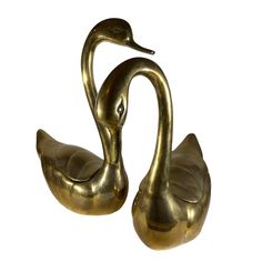 two brass swan figurines sitting next to each other on a white background,