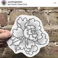 a hand holding up a sticker with an image of a flower in black and white