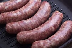 four sausages are cooking on the grill