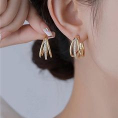 a close up of a person wearing gold ear clips with diamonds on them and a pearl in the middle