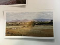 two pictures are hanging on the wall next to each other, and one has an open field with animals in it