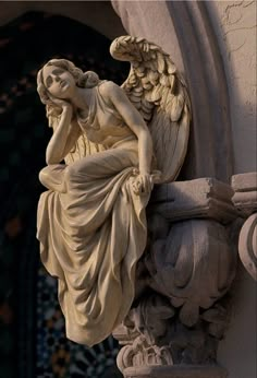 an angel statue sitting on the side of a building