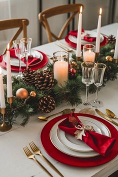 a christmas table setting with candles, plates and napkins