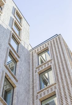 two tall brick buildings next to each other on a sunny day with blue sky in the background