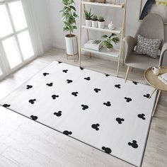 a living room with mickey mouse rugs on the floor and potted plants in the corner