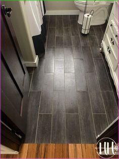 a bathroom with dark wood floors and white cabinets