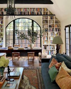 a living room filled with lots of furniture and bookshelves next to a window