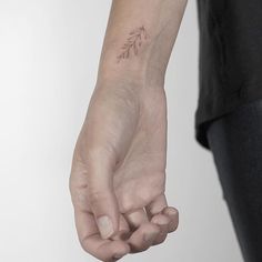 a person with a small tattoo on their left wrist holding the hand of another person