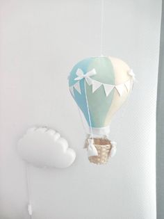 a hot air balloon floating in the sky next to a cloud shaped kite on a string