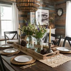 a wooden table topped with plates and vases filled with flowers on top of it