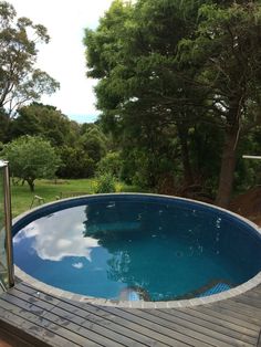 an empty swimming pool in the middle of a wooden decked area surrounded by trees