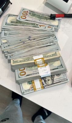 a pile of money sitting on top of a white table next to a laptop computer