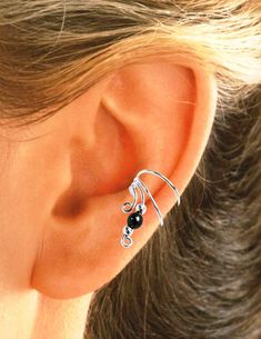 a woman's ear with two black beads on it