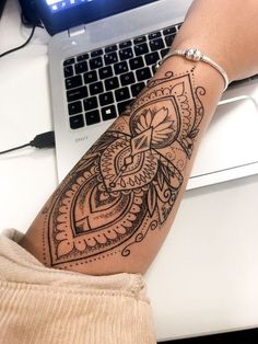 a person with a tattoo on their arm next to a laptop