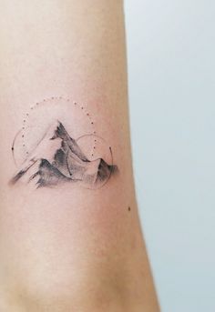 a tattoo on the arm of a woman with mountains and stars in the sky behind it