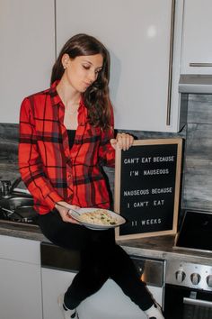 a woman sitting on top of a counter holding a plate of food