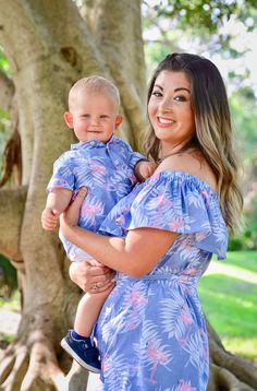 a woman holding a baby in front of a tree