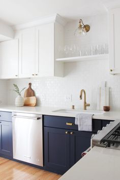 a kitchen with blue cabinets and white counter tops, gold pulls on the dishwasher