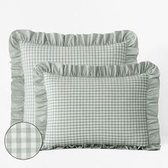 two pillows with ruffles on them sitting next to each other