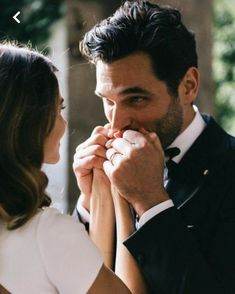 a man and woman standing next to each other with their hands on their mouths, looking at each other