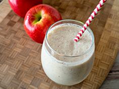 an apple smoothie in a glass next to two apples