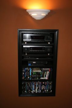 there is a wall mounted dvd rack with many movies on it and a remote control