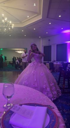 a woman in a ball gown standing next to a table with plates and glasses on it