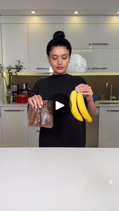 a woman is holding two bananas in her hand and looking at the bag she's holding