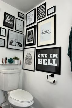 a white toilet sitting in a bathroom next to a wall with pictures on the walls