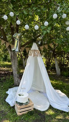 a teepee tent is set up in the grass under a tree with decorations on it