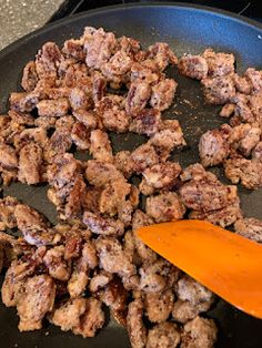 the food is being cooked in the skillet with an orange spatula next to it