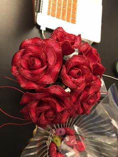 a bouquet of red flowers sitting on top of a table next to a laptop computer