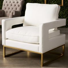 a white chair sitting on top of a wooden floor next to a wall with green plants