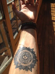 a person's arm with a sunflower tattoo on it and a window in the background