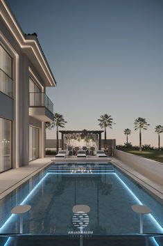 an outdoor swimming pool with lounge chairs and palm trees in the background at night time