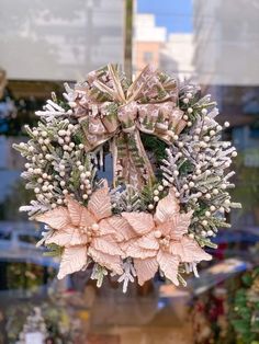 a christmas wreath hanging from the side of a store front window with pink and white flowers on it