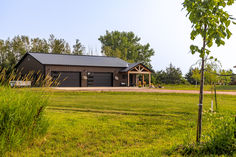 a large brown barn sitting on top of a lush green field