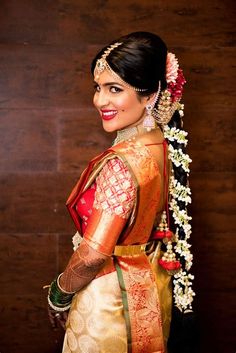 a woman in a red and gold sari with flowers on her head is posing for the camera