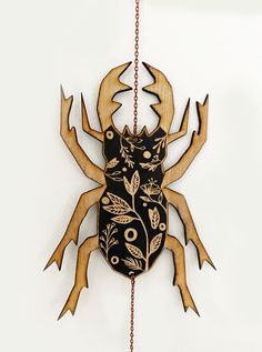 a wooden clock with an insect on it's face and chain hanging from the side