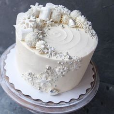 a white frosted cake with snowflakes and decorations on the top is sitting on a platter