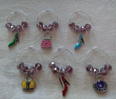 six wine glasses with charms on them sitting on a white tablecloth covered table cloth