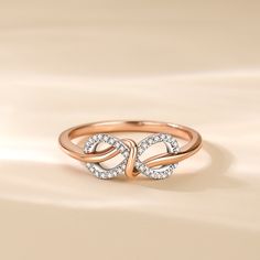 a rose gold ring with two intertwined hearts in the middle and diamonds on each band