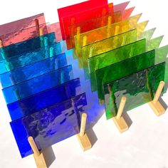 there are four different colored pieces of glass on wooden sticks in front of each other