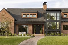 a large brick house with lots of windows on it's sides and a walkway leading to the front door