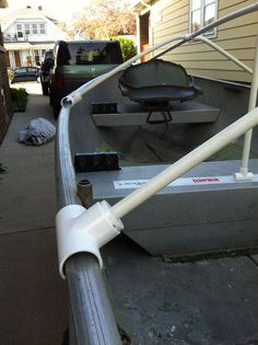 a boat sitting on the side of a road next to a house with a metal railing