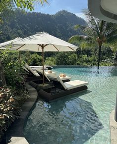 an outdoor pool with lounge chairs and umbrellas