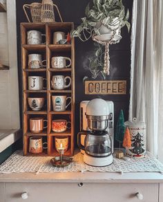 a coffee maker sitting on top of a counter next to a wooden box filled with cups