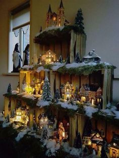 a christmas tree made out of wooden shelves with lights on them and snow covered trees