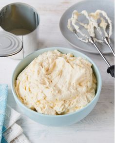 a bowl filled with whipped cream next to a whisk and some other items